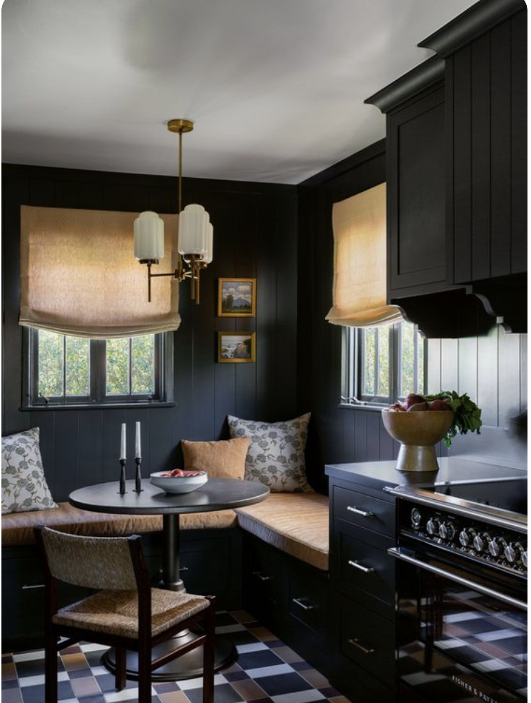 a black breakfast nook with a banquette and windows 